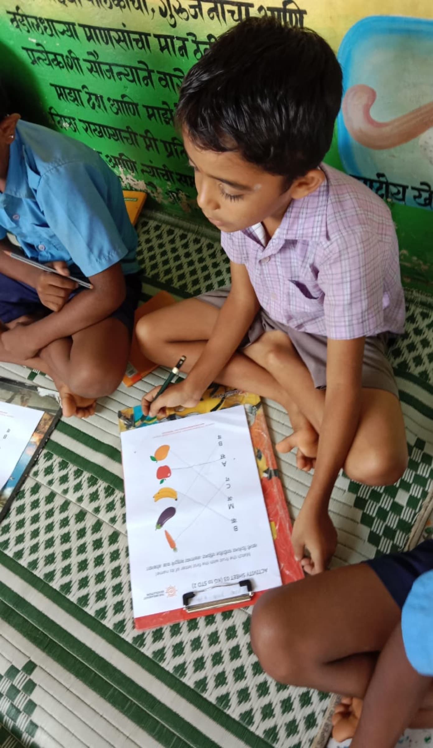 A boy works through a nutrition activity sheet, matching foods to letters.