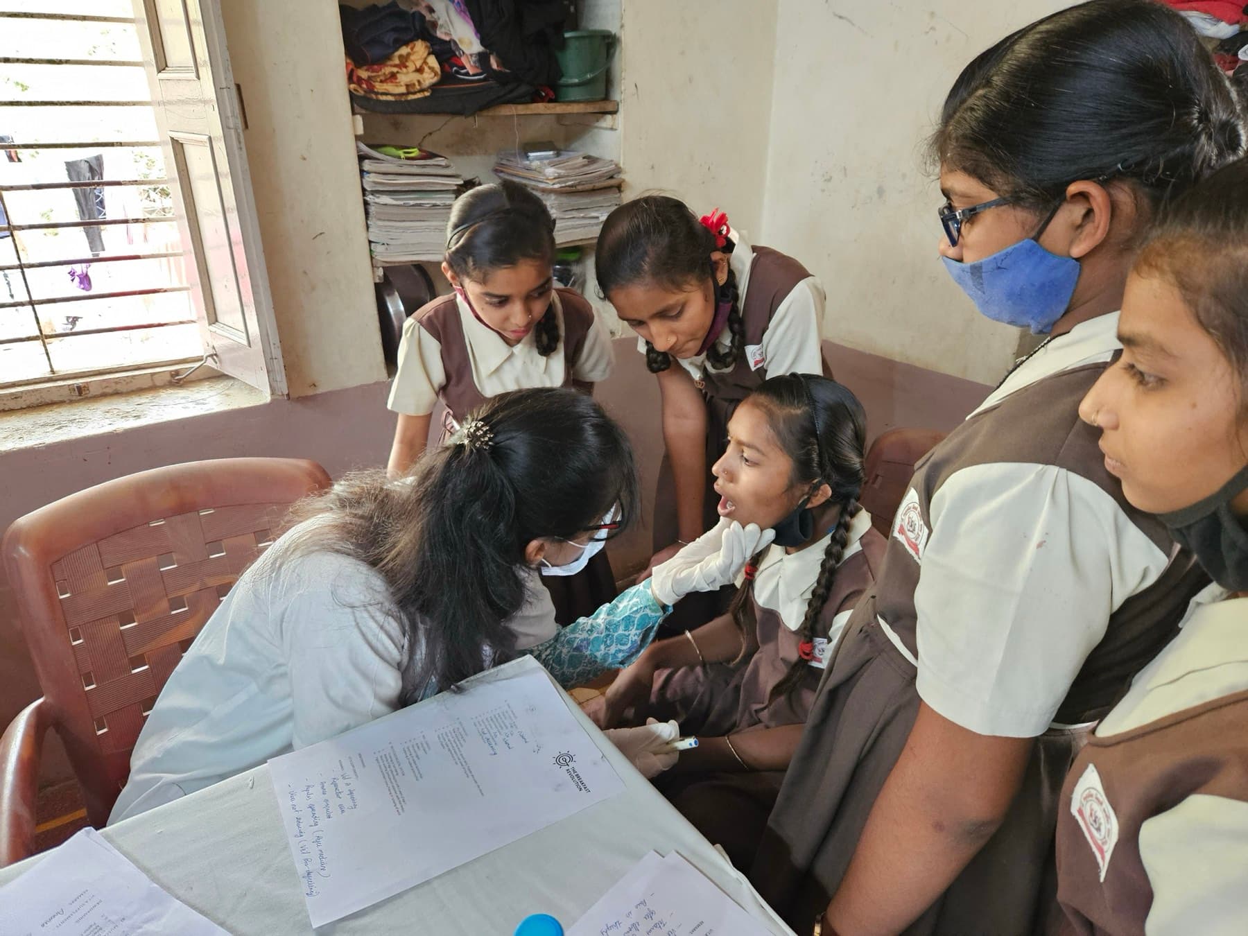 A health worker checks a student during a school screening as classmates look on.
