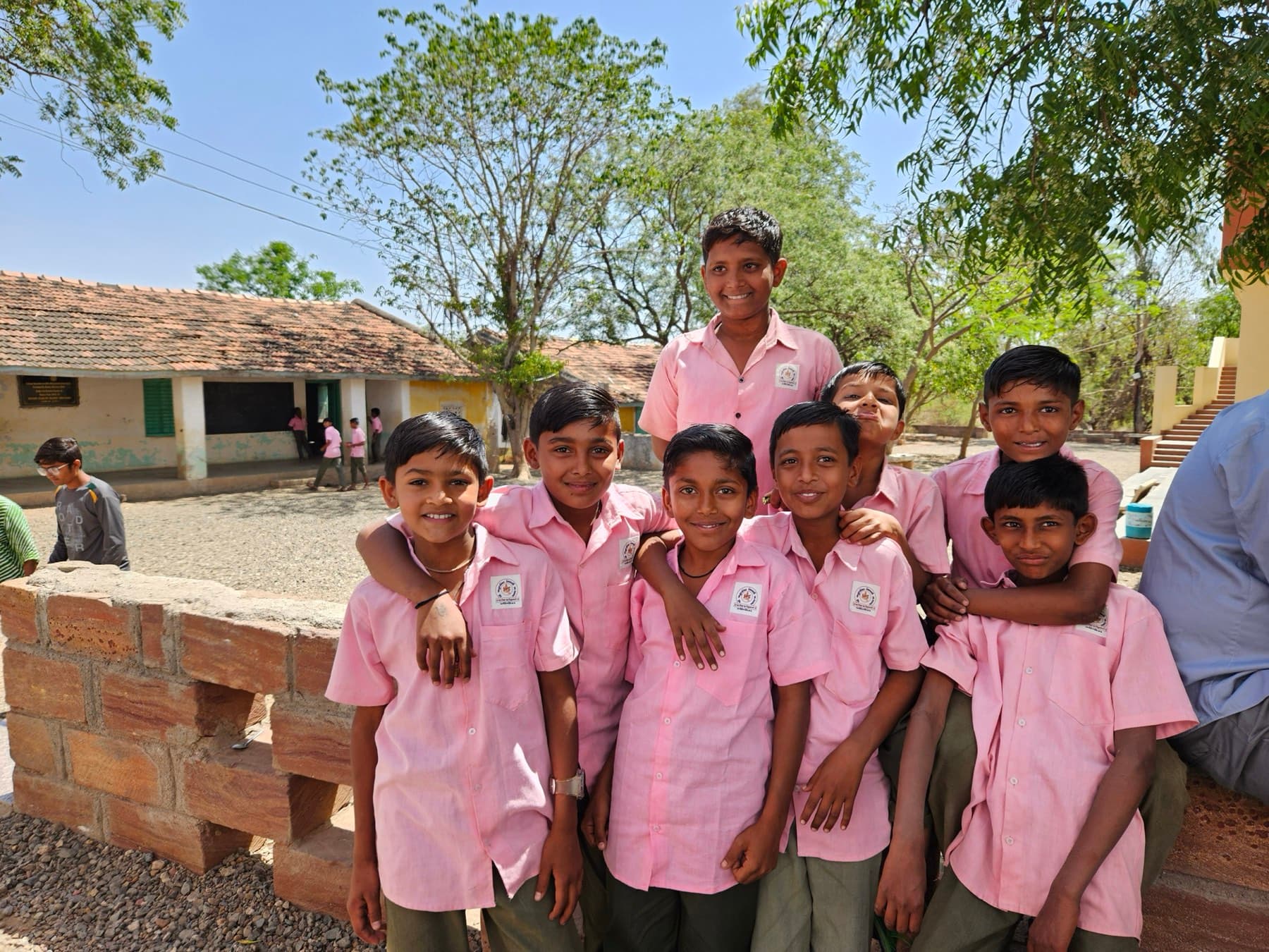 Pupils in bright uniforms gathered in a rural school courtyard for a morning session.