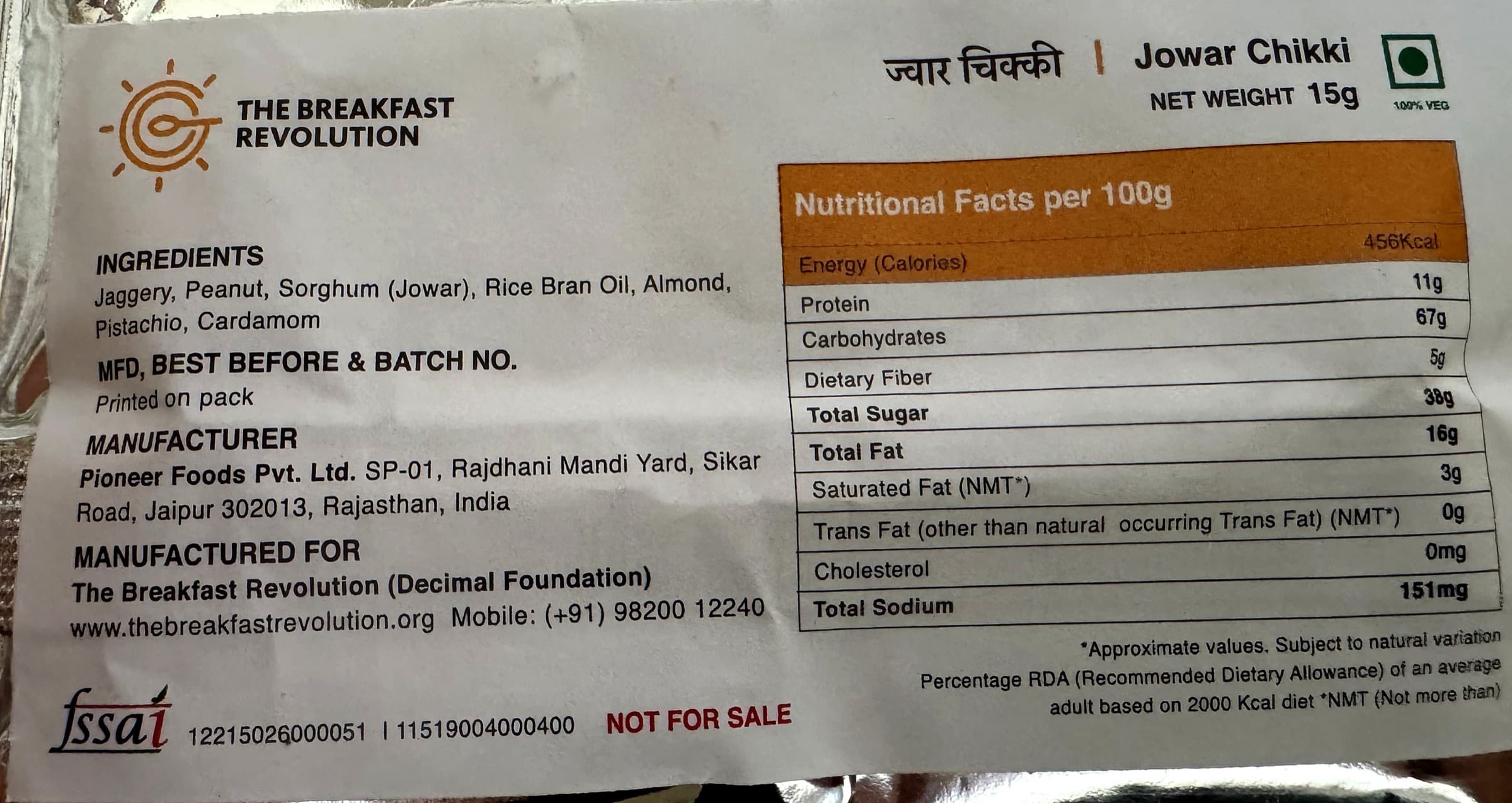 Photo of the printed label on a TBR Jowar Chikki pack: ingredients on the left, the nutrition facts panel on the right, every value given per 100 grams.